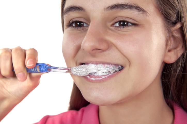 Close up of a girl brushing her braces and teeth.
