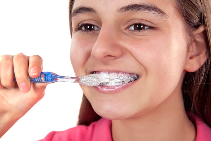 Close up of a girl brushing her braces and teeth.