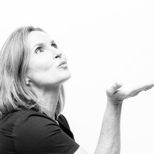 A black and white photo of an adult woman blowing a kiss.