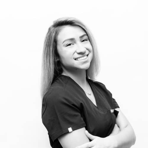 A black and white photo of a woman smiling with her arms crossed.