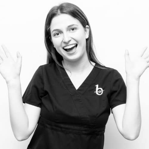 A black and white photo of a brown haired woman smiling and doing jazz hands.