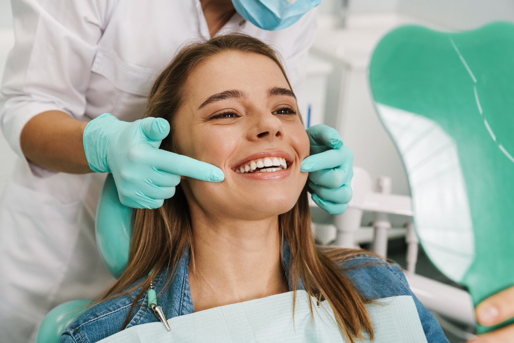 Orthodontist with a mask pointing to a girl's smile.