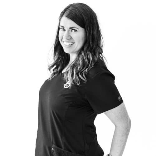 a patient care coordinator in black scrubs smiling at the camera with her hands on her hips.