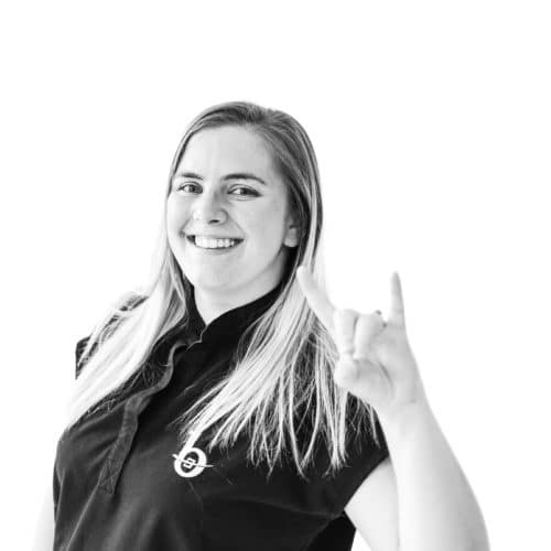 an orthodontic assistant smiling at the camera and doing the rock on hand sign.